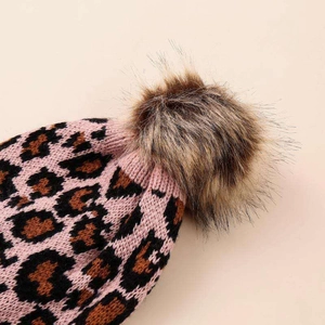 Detail view of pink leopard print knit hat with soft faux fur pompom top