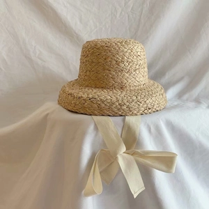 French style raffia straw hat for kids featuring a cream ribbon bow on white fabric
