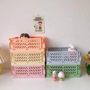 Stack of colorful foldable plastic storage crates in pastel colors on a white surface