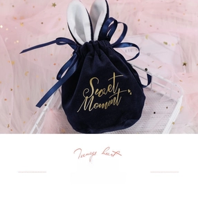 Detail of dark blue velvet wedding favor bag with bunny ears and gold Sweet Moment logo