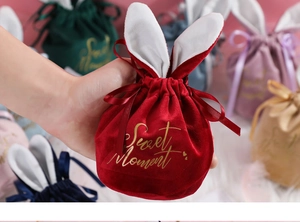 Detail of red velvet drawstring wedding favors bag with cute rabbit ears and gold text