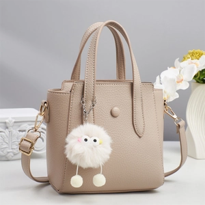 Minimalist beige pebble leather tote bag with a cute plush monster charm and top handles
