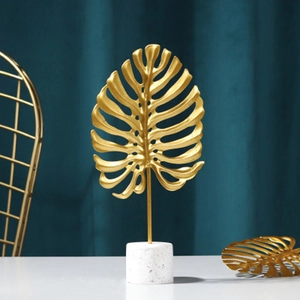 Golden monstera leaf sculpture with white marble base for modern home decor