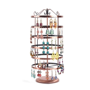 Detail view of a bronze rotating earring organizer with multiple tiers on white background