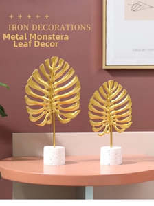 Close-up of golden iron monstera leaves with white marble bases on a pink table