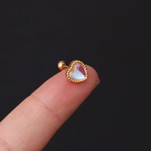 Macro shot of gold heart-shaped moonstone stud earring with screw back on fingertip