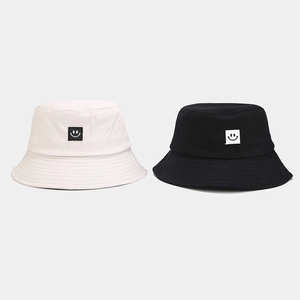Detail of cotton bucket hats in black and white with minimalist smile face patch