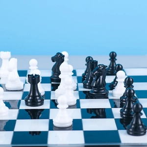 Detailed view of glossy black and white resin chess pieces on a mirror-like board