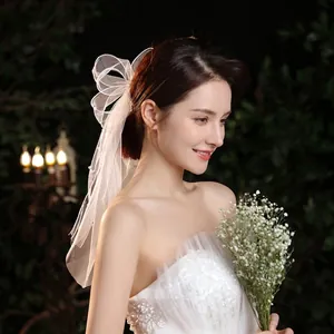 Elegant white bridal bow veil with pearl accents and delicate mesh for wedding styling