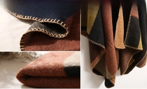 Detail of color-block knit poncho showing thick texture and decorative edge stitching