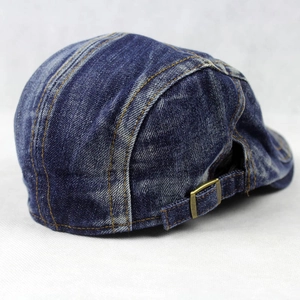 Close-up of vintage blue denim beret showing copper metal buckle and fabric texture