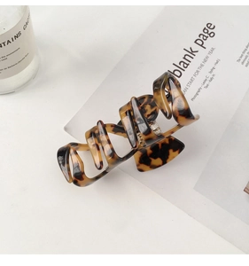 Detailed top view of a classic amber leopard tortoiseshell hair claw on a minimalist background