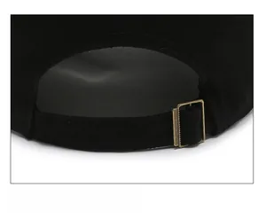Detail of adjustable cotton strap and bronze metal buckle on a black baseball cap