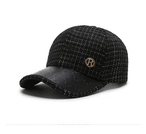 Detail of black tweed baseball cap with leather brim and gold metal letter R badge