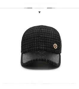 Detail of tweed baseball cap featuring black textured brim and gold crystal R emblem