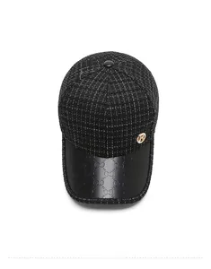 Detail of tweed baseball cap with gold B ornament and embossed black leather brim