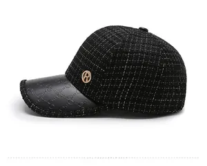 Detail of black tweed baseball cap with textured leather brim and golden R metal logo