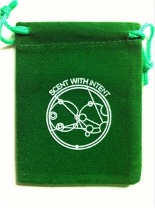 Close-up of green velvet drawstring jewelry pouch with white Scent With Intent logo print
