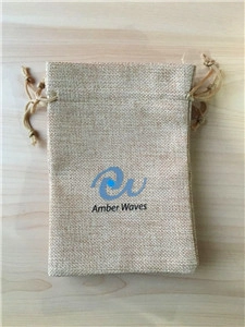 Detail of light brown drawstring linen pouch with blue Amber Waves logo on wood surface