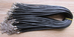 Detail of bundled black waxed cord necklaces with silver lobster clasps on wood