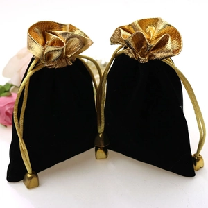 Close-up of black velvet jewelry pouches with gold drawstring and metallic trim details
