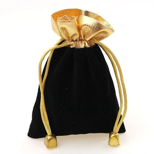 Detail of black velvet drawstring pouch with golden trim and metallic gold cord beads