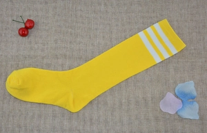 Detailed knit texture of yellow knee-high socks with three white stripes on burlap background
