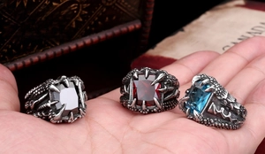 Macro detail of men's vintage dragon claw rings with black, red and blue zircon stones