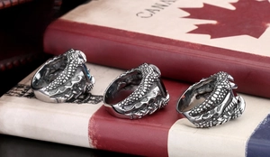 Macro detail of retro dragon claw rings with blue black and red gems on vintage book