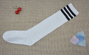 Close-up of white knee high socks with triple black stripes on a textured background