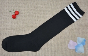 Detail of black over-the-knee socks with white triple stripes and knitted texture