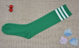Detail of green and white triple-striped cotton knee-high socks laid on burlap texture