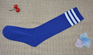 Flat lay of royal blue knee-high socks with three white stripes on burlap background