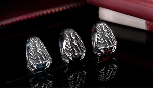 Macro detail of gothic dragon claw rings with red and blue zircon stones on black background