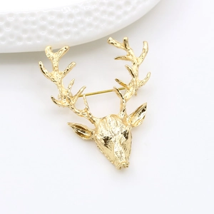 Détail d'une broche renne dorée montrant la texture des bois sur fond blanc pur
