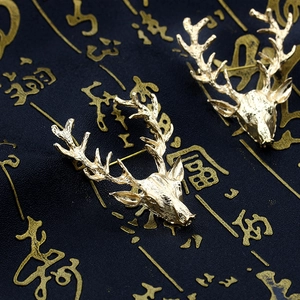Gros plan de deux broches tête d'élan dorées avec bois détaillés et textures métalliques