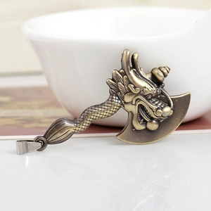 Antique bronze dragon head axe pendant DIY jewelry accessory in a white ceramic bowl