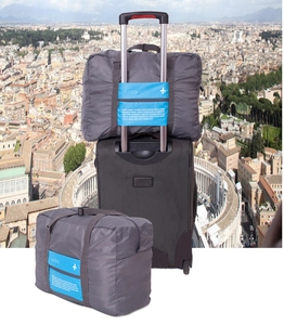 Detail of gray foldable waterproof travel bag with blue suitcase handle strap
