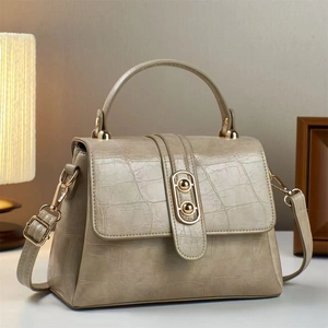 Detailed macro view of khaki faux leather handbag with crocodile pattern and gold buckle