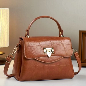 Brown crocodile embossed tote bag with gold arrow clasp on a domestic background