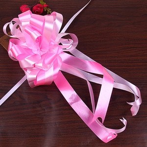 Detail of a large pink and white double-layer ribbon bow on a dark wood background