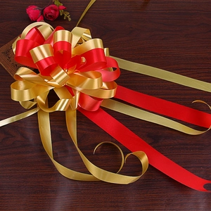 Close-up of a large red and gold dual-layer ribbon pull bow for gift decoration