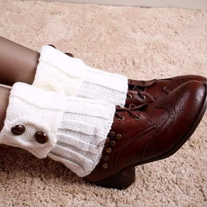Detail view of white knit leg warmers with two buttons worn with brown brogue boots