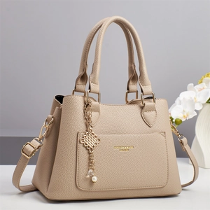 Elegant beige leather handbag for women with dual handles and gold pearl pendant charm
