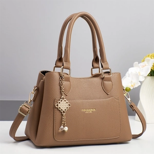 Elegant brown pebbled leather handbag with gold hardware and decorative pearl pendant charm