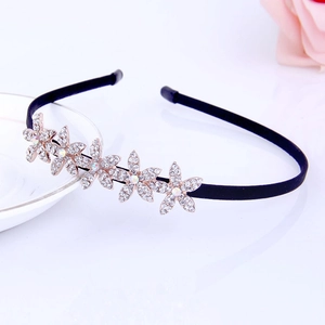 Close-up of elegant black headband with five rhinestone flowers on a white tray
