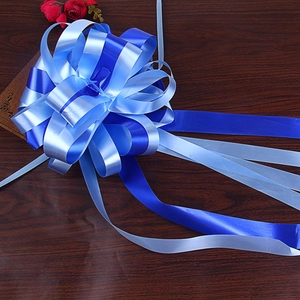 Macro shot of a layered navy and light blue decorative pull bow on dark wood background