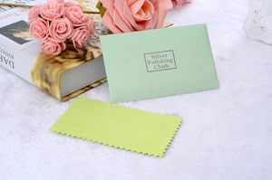Close-up of light green silver polishing cloth and matching paper envelope packaging