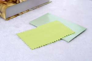 Detail of yellow polishing cloth with serrated edges and a soft green greeting card