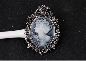 Detailed view of a vintage cameo brooch featuring an antique silver floral frame with rhinestones
